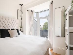 a white bedroom with a large bed and a window at Fore Street House - Apartment 2 in Seaton