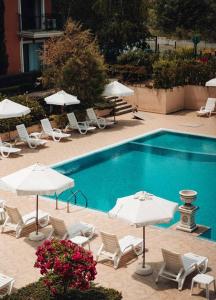 a swimming pool with white umbrellas and chairs and tables at Lovely apartment near Kavatsi in Sozopol