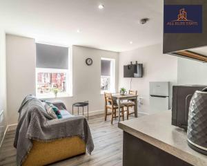 eine Küche und ein Wohnzimmer mit einer Couch und einem Tisch in der Unterkunft Swan House Apartment 2 - 1 Bed Apartment - Sleeps up to 4 - Free Parking - Liverpool - close to city centre - By ALL ELITE STAYS in Liverpool