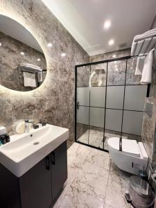 Un baño con lavabo, inodoro y espejo. en Royal Mass Airport Business Hotel, en Arnavutköy