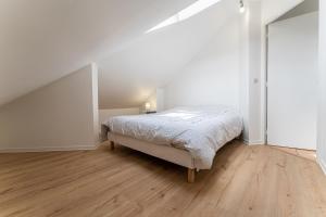 a white bedroom with a bed and a wooden floor at Poissy - Ma Résidence Privée in Poissy