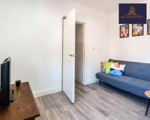 ein Wohnzimmer mit einem blauen Sofa und einem TV in der Unterkunft Swan House Stunning 1 bed Apartment By ALL ELITE STAYS - near Liverpool city centre - Sleeps 4 - Free Parking in Liverpool