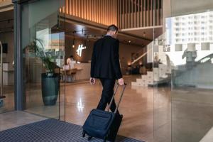 Holiday Inn & Suites - Dubai Science Park, an IHG Hotel في دبي: رجل في بدلة يسحب حقيبة