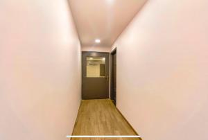 a hallway with a black door and a wooden floor at FabExpress Heera Holiday Inn - Nr Eden Garden Stadium in Kolkata