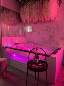 a pink room with a tub with a table and wine glasses at Superbe appartement avec Balnéothérapie/spa/ Champagne in Pornic