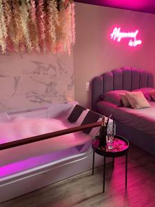 ein rosafarbenes Zimmer mit 2 Betten und einem Tisch in der Unterkunft Superbe appartement avec Balnéothérapie/spa/ Champagne in Pornic