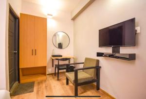 a room with a tv and a chair and a table at FabHotel Heera Holiday Inn in Kolkata