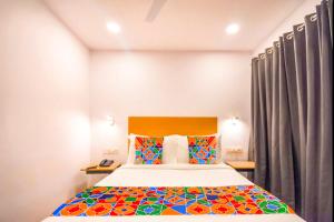 a bedroom with a large bed with colorful pillows at FabHotel Heera Holiday Inn in Kolkata