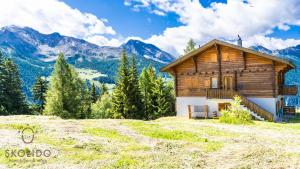 a log cabin on a hill with mountains in the background at Ferienwohnung Chalet Bortelhorn in Termen