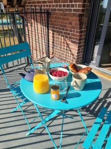 einen blauen Tisch mit Frühstücksspeisen auf der Veranda in der Unterkunft Les terres de Marie - Logements calmes et modernes 
