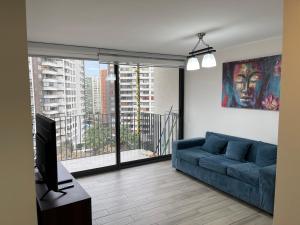 a living room with a blue couch and a large window at Paso mall vespucio in Santiago