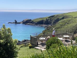 a man standing on a deck looking at the ocean at Old Temperance House B&B St Keverne in Saint Keverne
