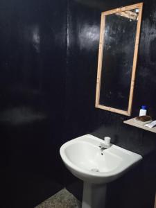 La salle de bains est pourvue d'un lavabo blanc et d'un miroir. dans l'établissement Cozy House Hostel, à Ella