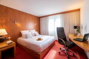 Pokój hotelowy z łóżkiem, biurkiem i laptopem w obiekcie CERISE Bordeaux Mérignac Aéroport w mieście Mérignac