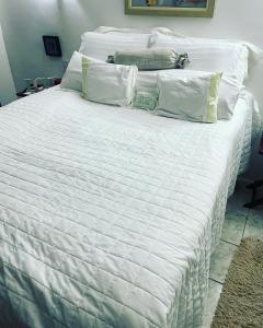 Una cama blanca con sábanas blancas y almohadas. en Chalé romântico , rústico e vista de tirar o fôlego en Guaramiranga