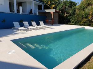 a swimming pool with chairs and a house at Les Coeurs d'Amants in Saint-Joseph