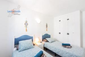 a bedroom with two beds with blue pillows at Lima Vivienda Vacacional in Puerto del Carmen