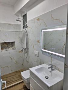 La salle de bains blanche est pourvue d'un lavabo et d'une douche. dans l'établissement Flower Hill, à Vlorë