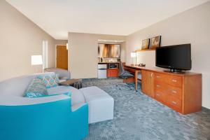 a living room with a couch and a desk with a tv at Courtyard by Marriott Savannah Midtown in Savannah