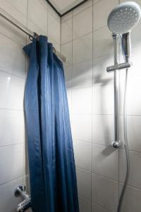 a shower with a blue shower curtain in a bathroom at Appartement Zuiderstrand in Zoutelande