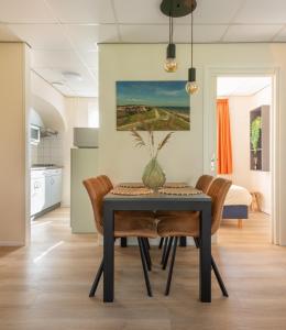 a dining room table with chairs and a vase on it at Appartement Zuiderstrand in Zoutelande