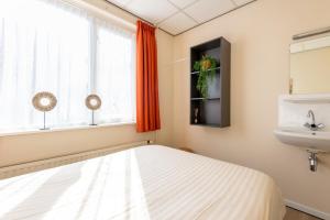 een slaapkamer met een bed, een wastafel en een raam bij Appartement Zuiderstrand in Zoutelande