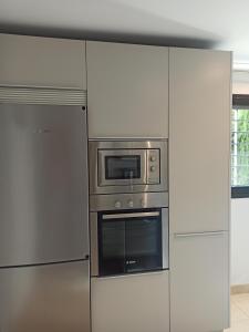 una cucina con elettrodomestici in acciaio inossidabile e armadietti bianchi di Beach Apartment Puerto Banus Marbella a Estepona