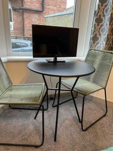 una mesa y dos sillas con un monitor de ordenador en 2 Bed ground floor apartment, sleeps 4 with free parking, en Harrogate