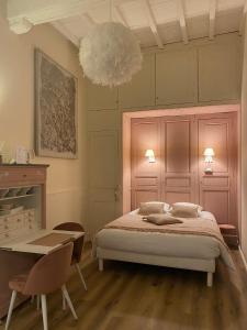 ein Schlafzimmer mit einem Bett, einem Tisch und einem Kronleuchter in der Unterkunft Coeur de Calignac in Calignac