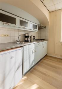 Appartement Zuiderstrand في زوتلاند: مطبخ مع دواليب بيضاء ومغسلة