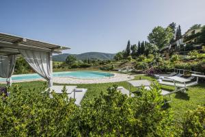 un patio trasero con piscina con sillas y avisor en Villa degli Amanti - Homelike Villas, en Terranuova Bracciolini
