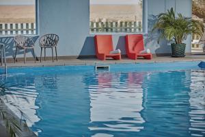 a swimming pool with chairs and chairs next to a beach at Moonfleet Manor Hotel in Weymouth