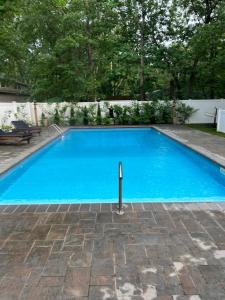 a swimming pool with blue water in a yard at Hamptons Getaway in East Quogue