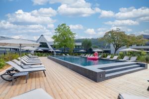une piscine avec des chaises longues et un flotteur rose dans l'établissement Miura, à Voglans