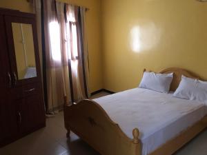 a bedroom with a bed with white sheets and a window at Résidence les Signares de Saint Louis in Saint-Louis