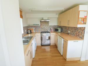 a kitchen with white appliances and wooden cabinets at 5 Forest Park Lodge in High Bickington