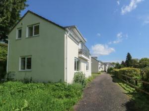 a green and white house with a gravel road at 5 Forest Park Lodge in High Bickington