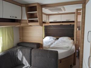 1 dormitorio pequeño con 1 cama en una caravana en Luxuswohnwagen Barsch am Kransburger See 003, en Kransburg