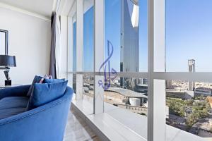 um sofá azul num quarto com uma janela grande em Walaa Homes Luxury 2Bedroom at DAMAC Exclusiva Tower Riyadh Saudia-1904 em Riade