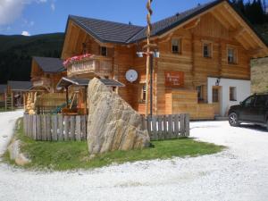 un grand rocher devant une cabane en rondins dans l'établissement Almrauschhütte Markus, à Lachtal