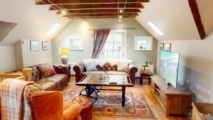 a living room with a couch and a table at The Maltings - lodge with hot tub in Nethy Bridge