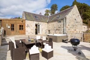 a patio with a table and chairs and a grill at The Maltings - lodge with hot tub in Nethy Bridge