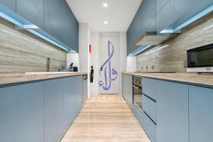 uma cozinha com armários azuis e um lavatório em Walaa Homes Luxury 2Bedroom at DAMAC Exclusiva Tower Riyadh Saudia-1904 em Riade