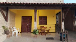 a yellow house with a table and chairs on a patio at Chalés Canto do Mar in Redonda
