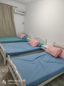 three beds in a hospital room with blue and pink pillows at North coast in El Alamein