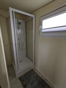 a bathroom with a shower with a glass door at Premiumwohnwagen Grauer Kranich am Kransburger See 43 in Kransburg