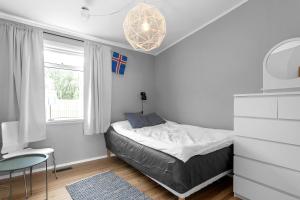 a small bedroom with a bed and a window at Family house with garden, Hot Tub Near Reykjavík in Garðabær