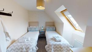 a attic room with two twin beds and a window at Eagle Lodge - Aviemore Lodges in Aviemore