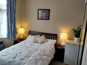 Amherst Guesthouse في ريدينغ: غرفة نوم بسرير مع شراشف بيضاء ومصباحين