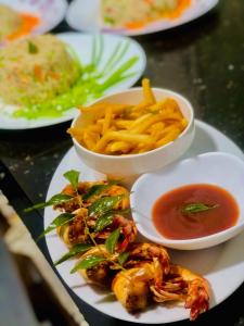a plate of food with french fries and dipping sauces at Shan Guest and Restaurant Nilaveli in Trincomalee